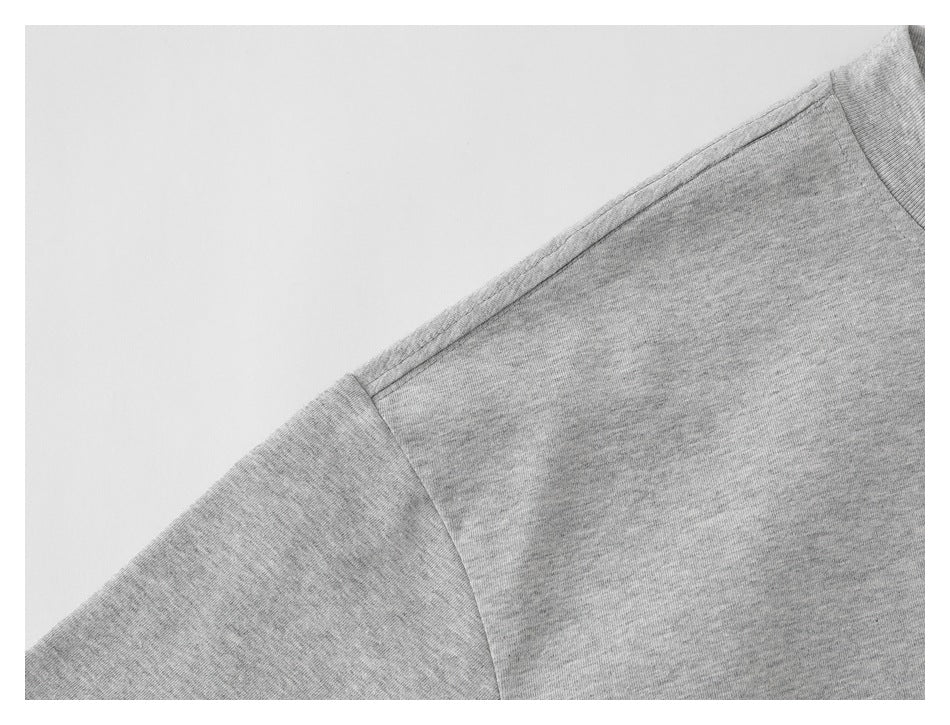 Close-up of the shoulder seam and sleeve of a heather-gray T-shirt.