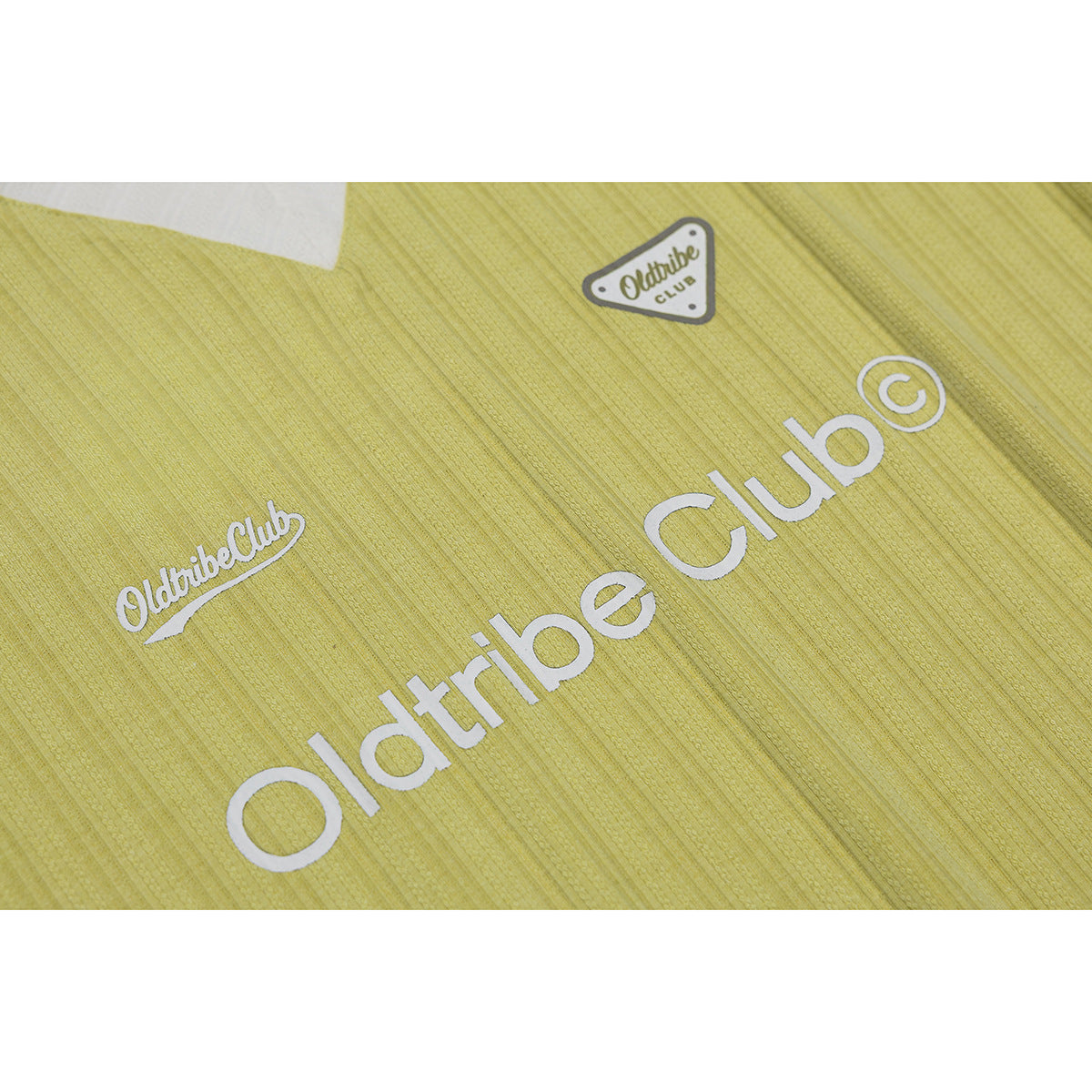 Close-up of a lime-yellow textured shirt chest with white Oldtribe Club lettering and badge.