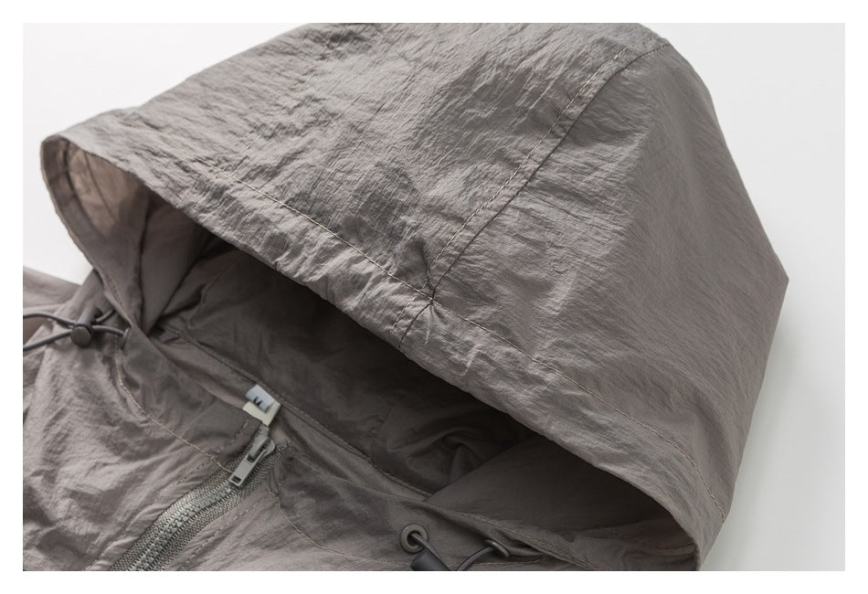 Close-up of gray jacket hood with stitching, drawcord toggles and zipper