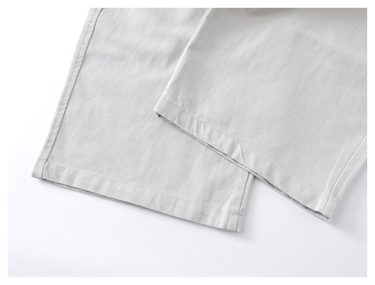 Close-up of the hems of light gray trousers, showing the stitching and diagonal weave.