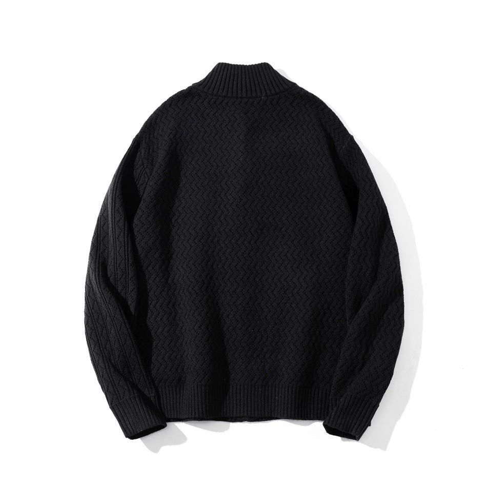 Back view of a black textured knit sweater laid flat, with a ribbed stand collar, cuffs, and hem.
