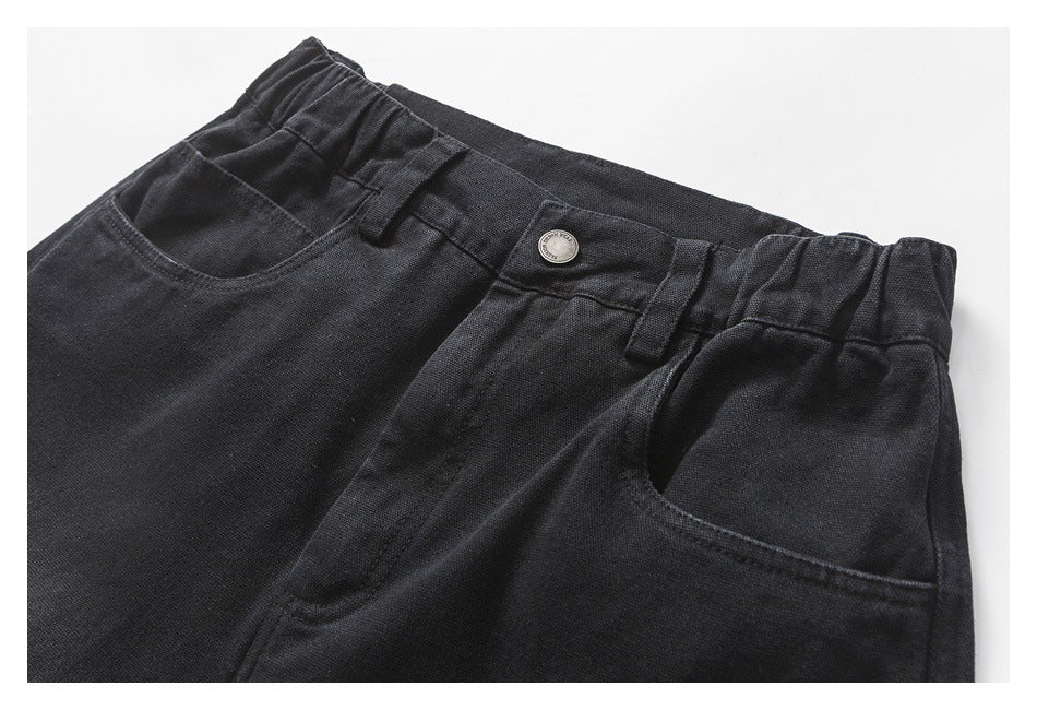Close-up of the front waistband of charcoal shorts, showing the button, belt loops and curved pockets.