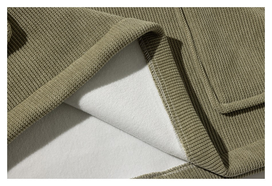 Close-up showing the inside of an olive ribbed garment seam and its stitched edge.