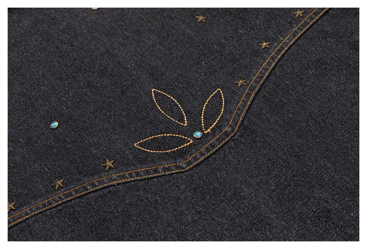 Dark denim detail with an orange stitched leaf motif, small blue studs, and bronze star studs.