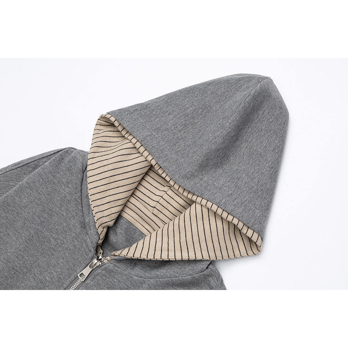 Close-up of a gray hoodie with its beige and black striped hood lining exposed.