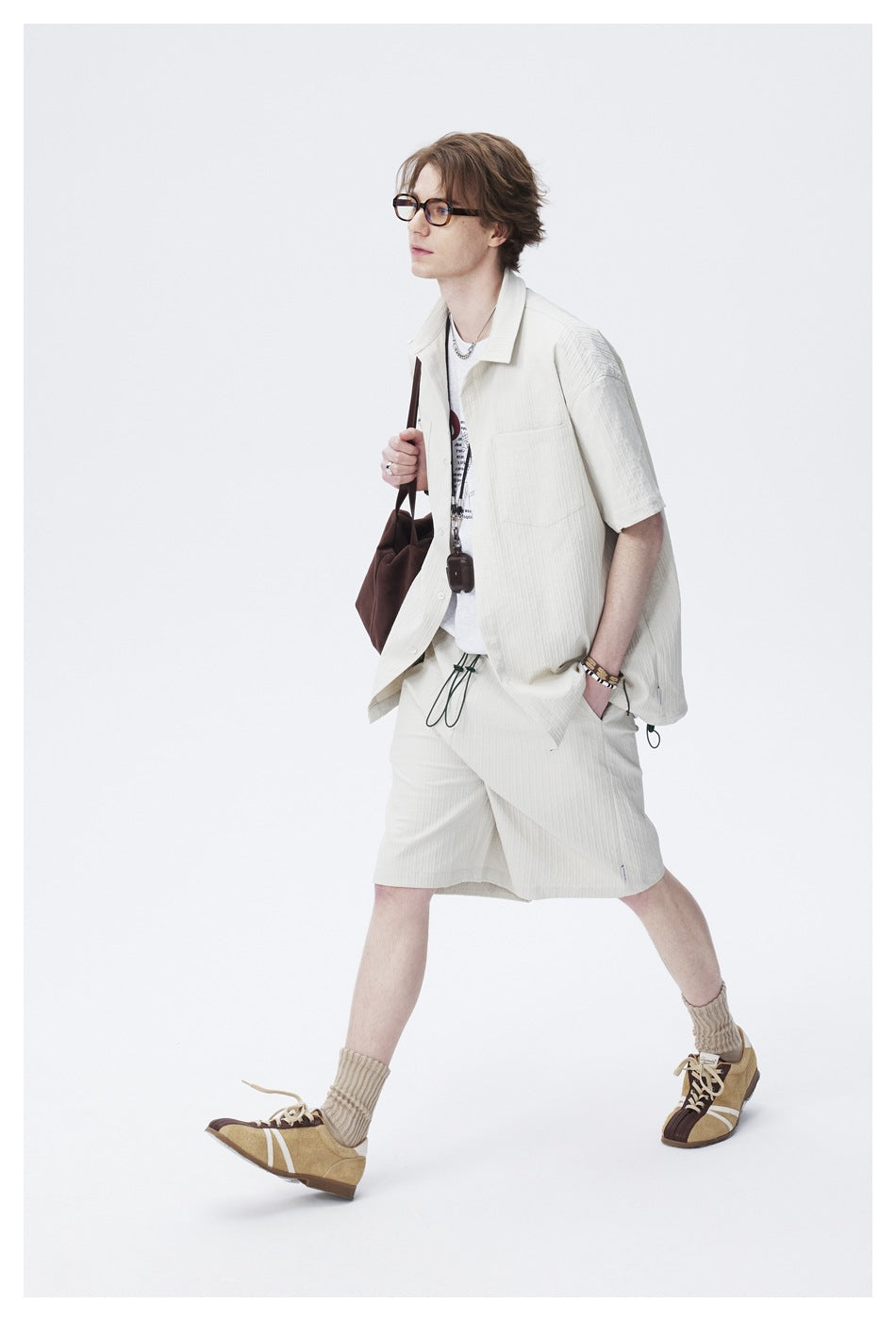 Full-length view of a model wearing an ivory short-sleeve shirt and matching drawstring shorts.