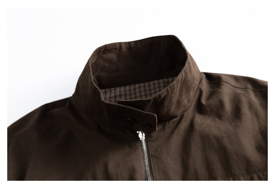 Close-up of the jacket’s dark stand collar, snap tab, zipper, and checked lining.