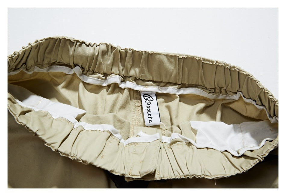 Inside view of beige trousers showing the gathered waistband, white lining, and sewn-in brand label.