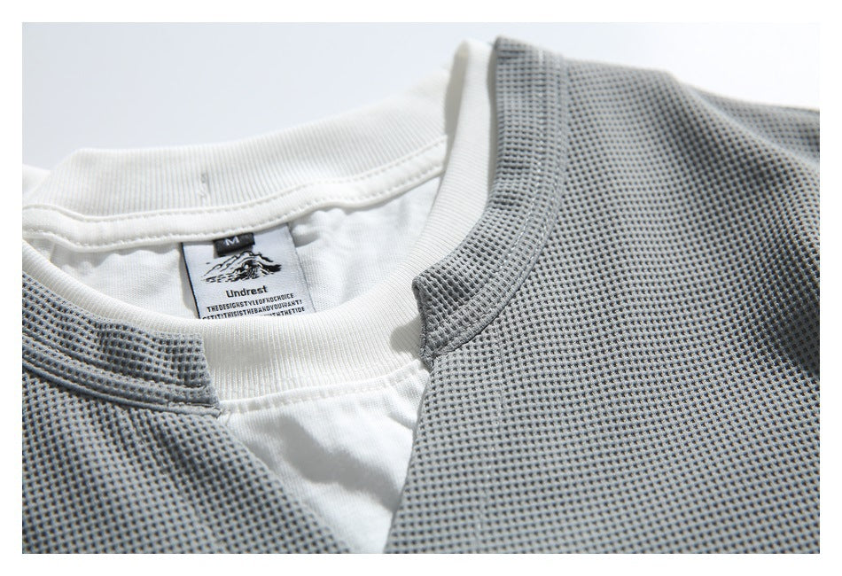 Close-up of the neckline and attached Undrest label on the gray textured top over a white layer.