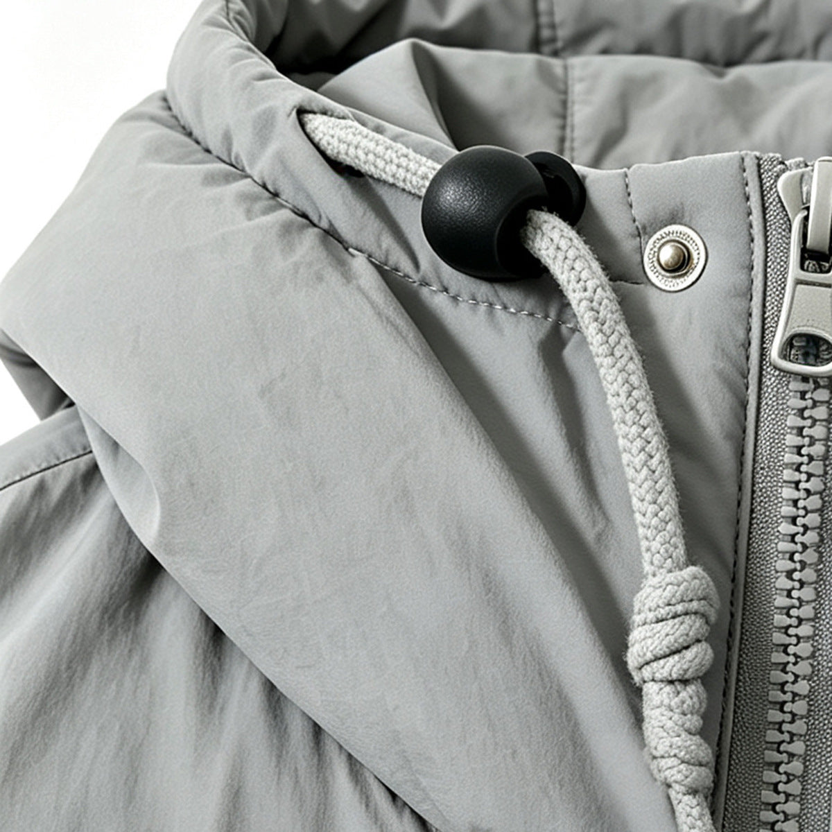 Close-up of the light gray jacket's hood drawcord, black cord lock, metal snap and zipper.