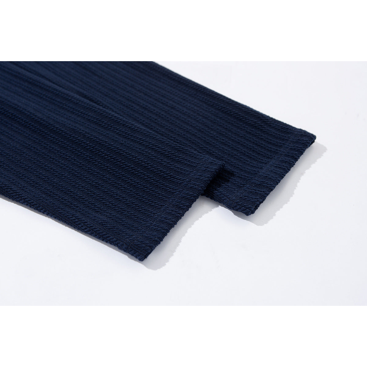 Close-up of the navy ribbed top's finished hem edges.