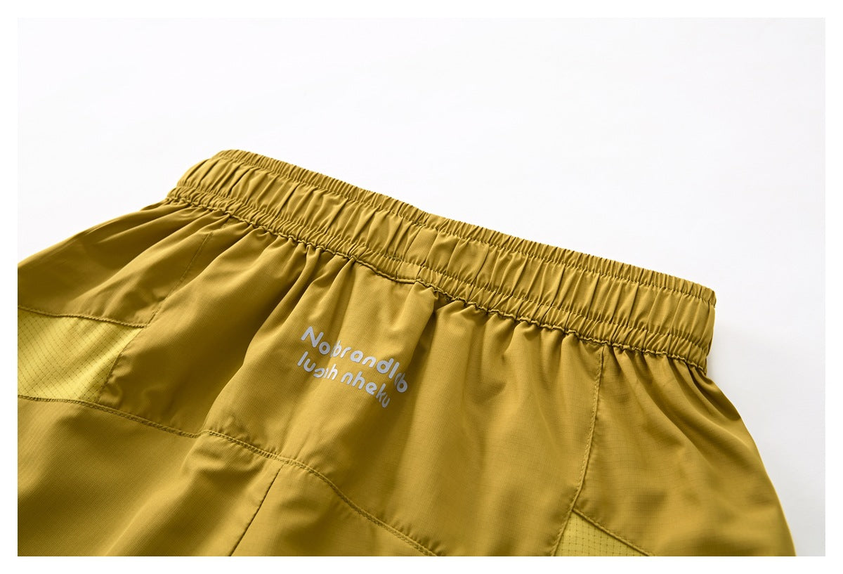 Angled close-up of the mustard shorts' elastic waistband, back panels and small white garment lettering.