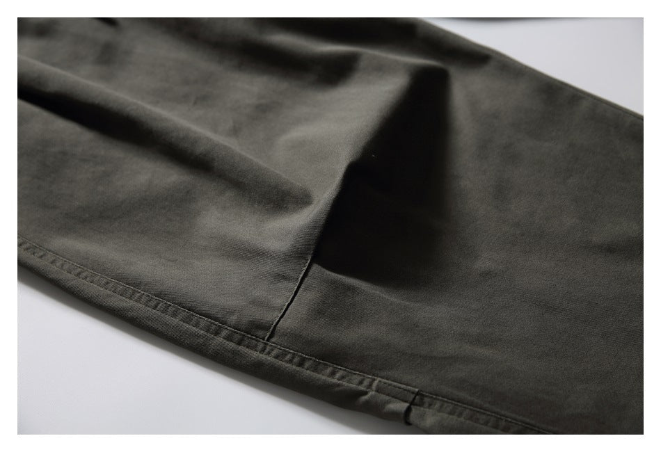 Close-up of dark olive-gray pant leg fabric and stitched hem.