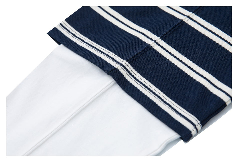 Close-up of navy fabric with white stripes folded over plain white fabric.