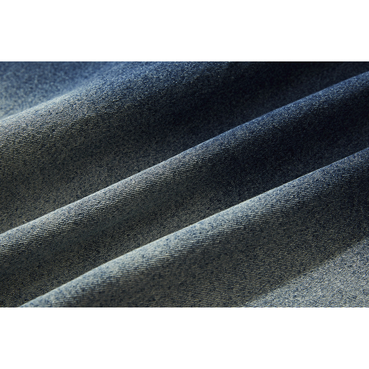 Close-up of dark blue denim fabric arranged in soft folds, showing its woven texture.