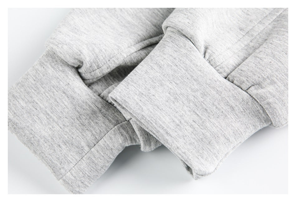 Close-up of overlapping folds and stitched edges on light gray heathered garment fabric.