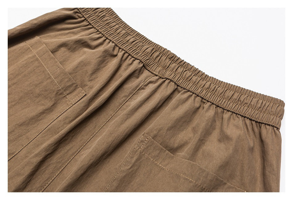 Brown trousers close-up showing an elastic waistband and large stitched pockets.