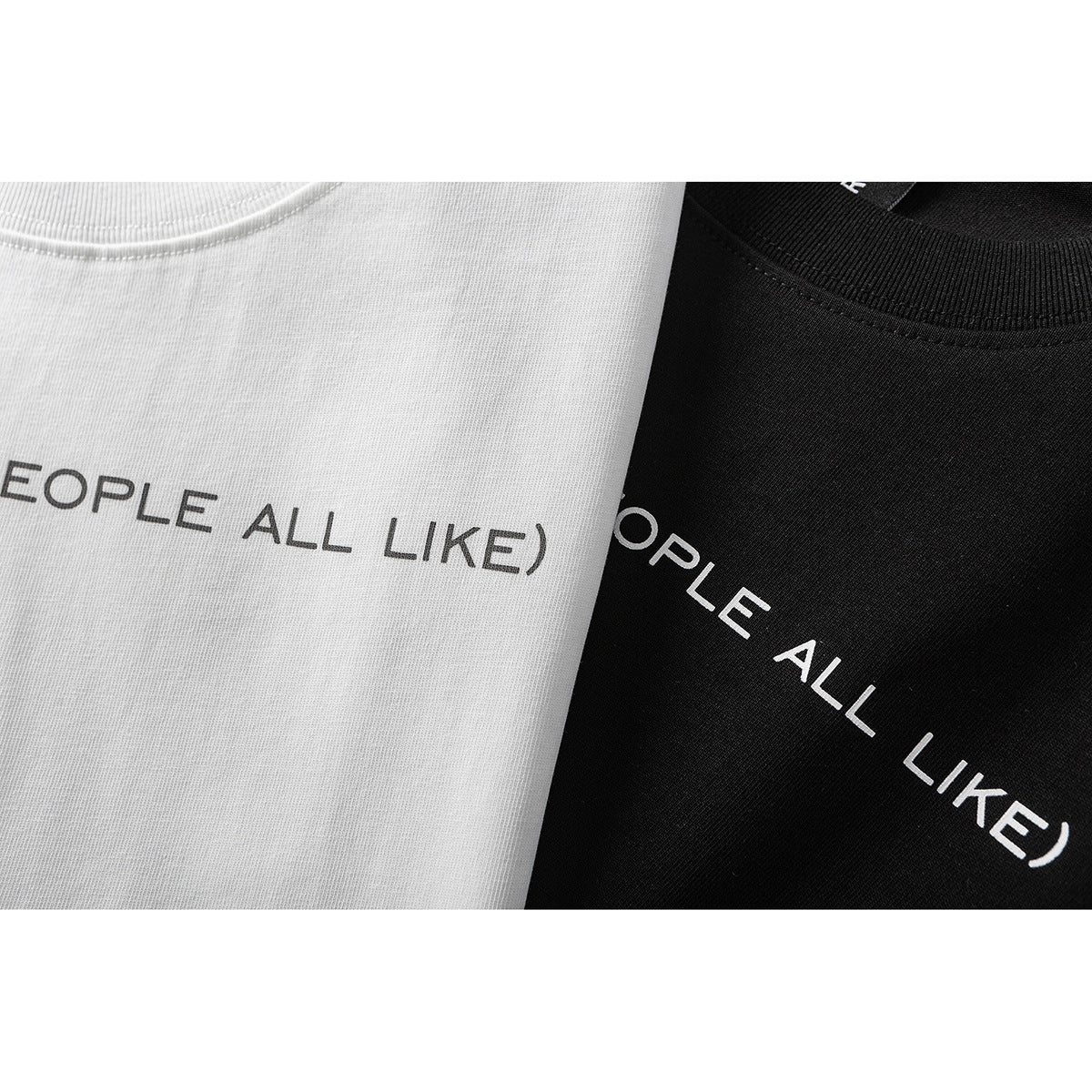 Close-up of white and black T-shirts with partial English lettering and ribbed crew necks.