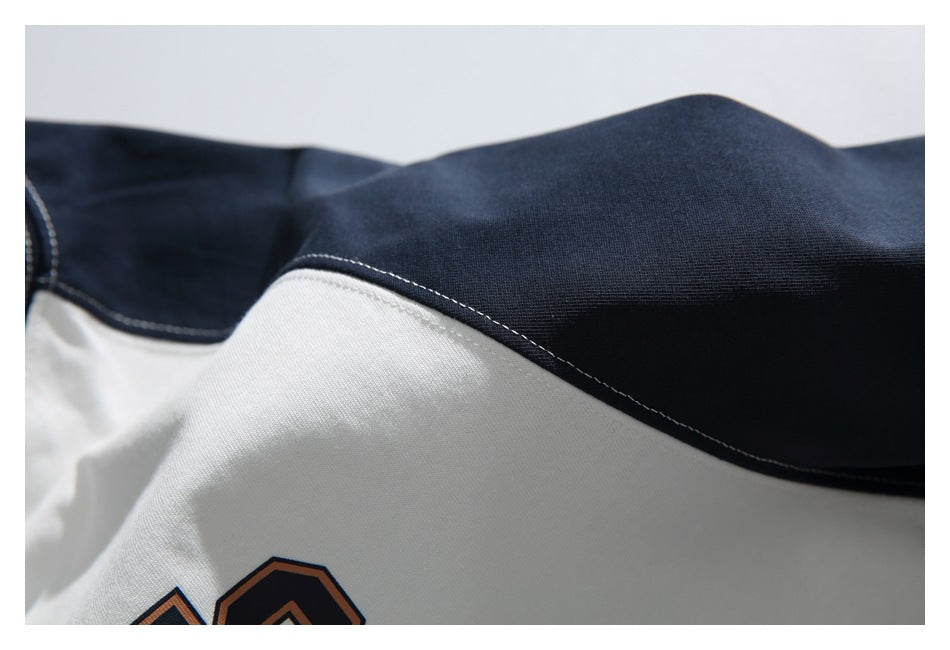 Close-up of the navy sleeve panel joined to the white shirt body with contrast stitching.