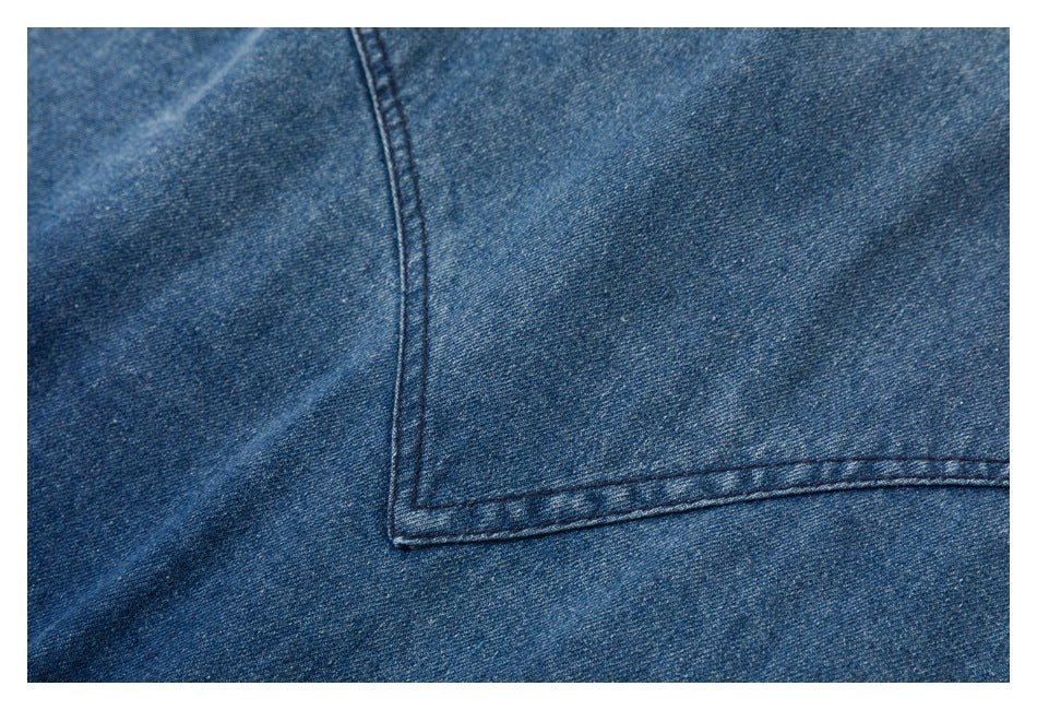 Close-up of blue denim fabric and a stitched pocket edge.