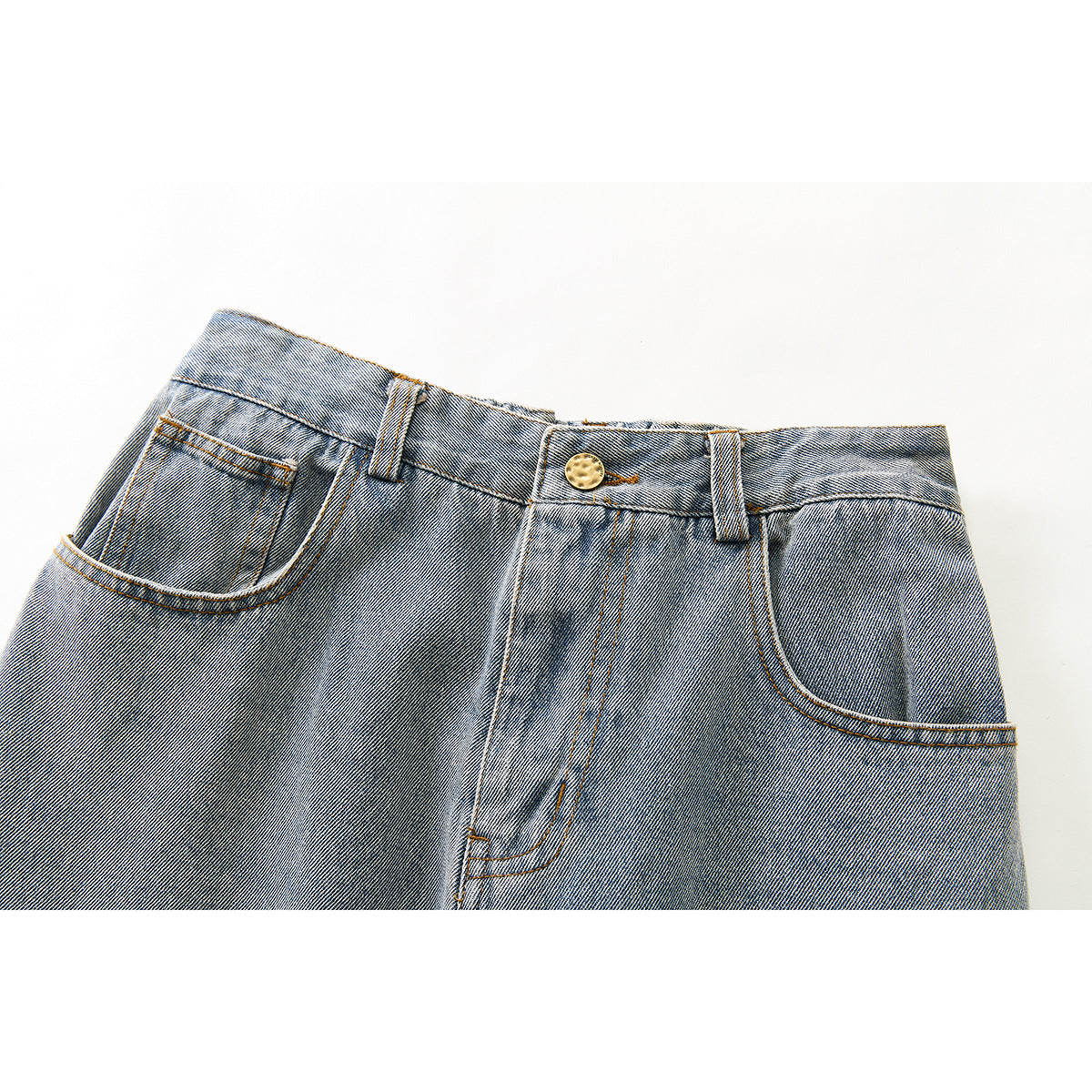 Close-up of the front waist of washed blue-gray jeans, showing the button, belt loops, fly and curved pockets.