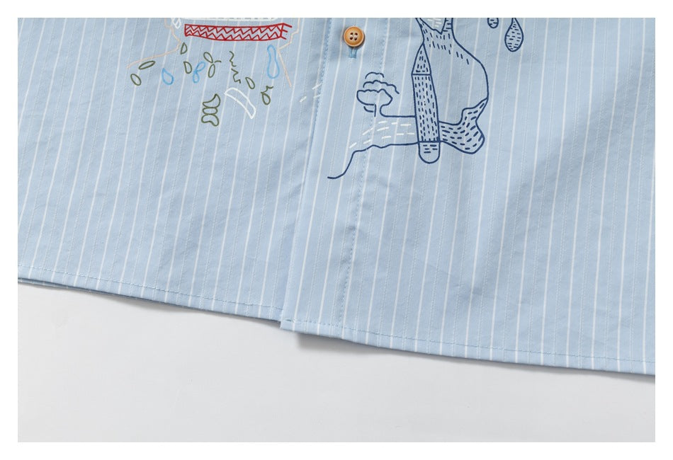 Close-up of the lower front of a light blue pinstriped shirt with partial decorative line-art graphics and a button.