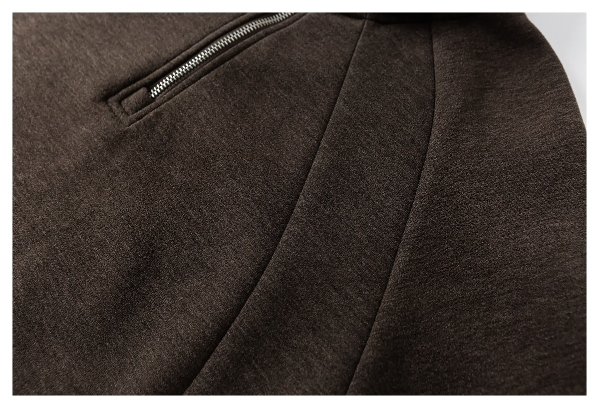Close-up of a dark brown coat’s angled zip pocket and curved panel seams.