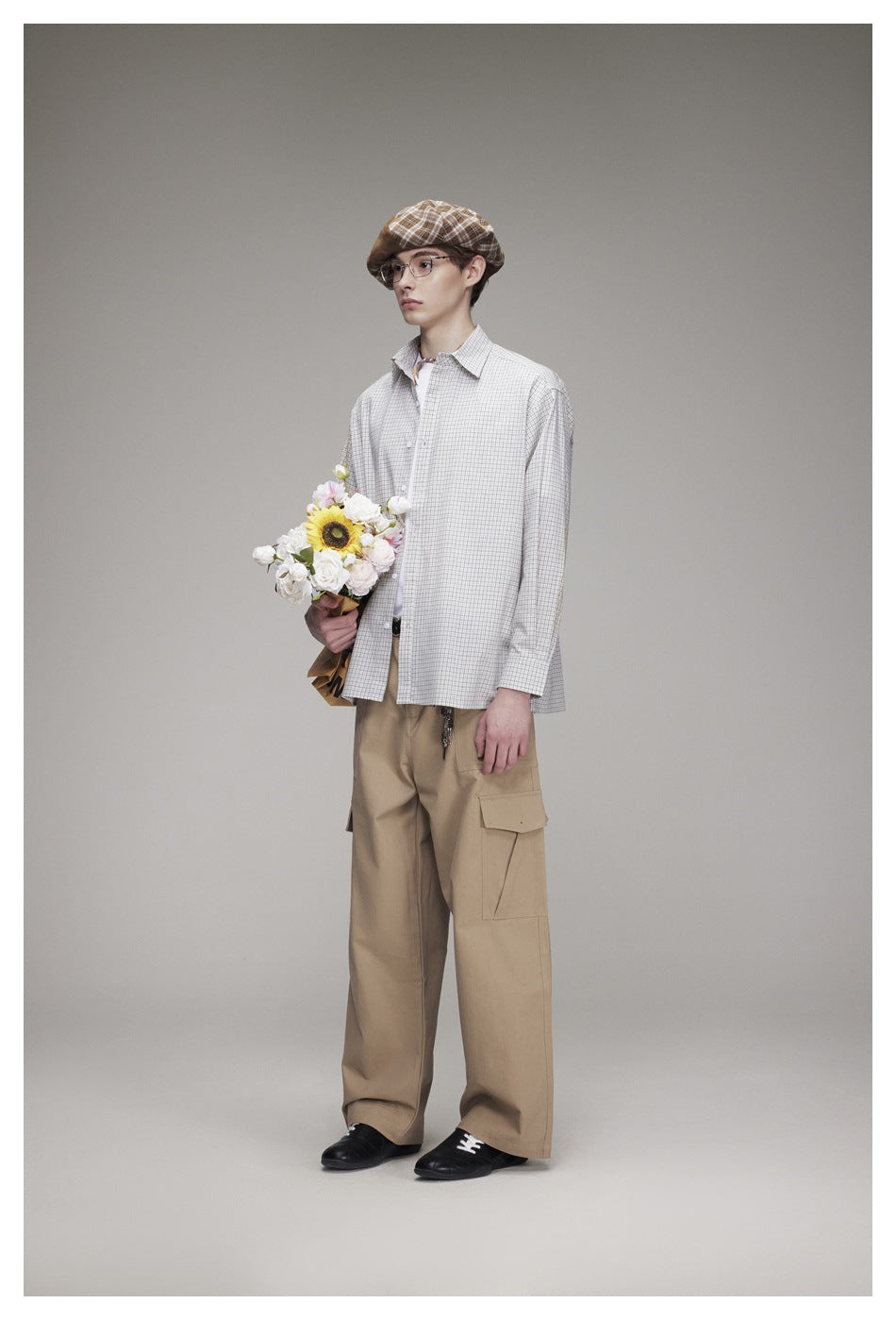 Three-quarter view of a model wearing a light gray checked shirt and tan cargo trousers.