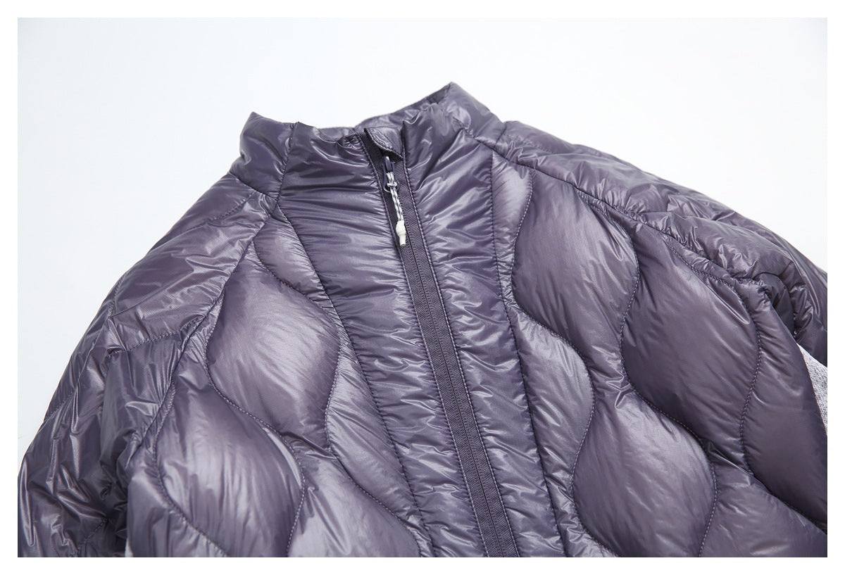 Close-up of the jacket’s padded collar, front zipper, and large quilted sections in muted gray-purple.