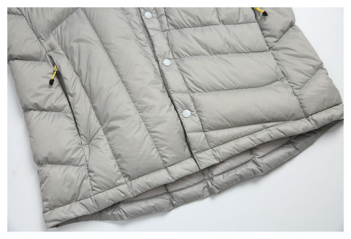 Close view of the gray quilted jacket's lower front, snap placket, side zipper pocket, and hem.