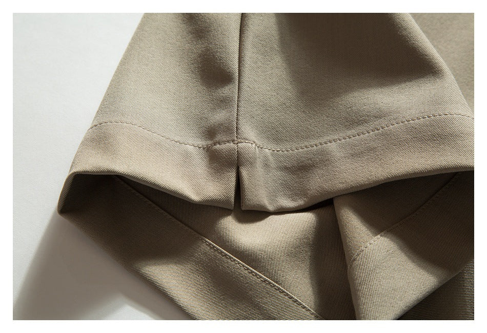 Close-up of a taupe trouser hem with a small center slit and visible stitching.