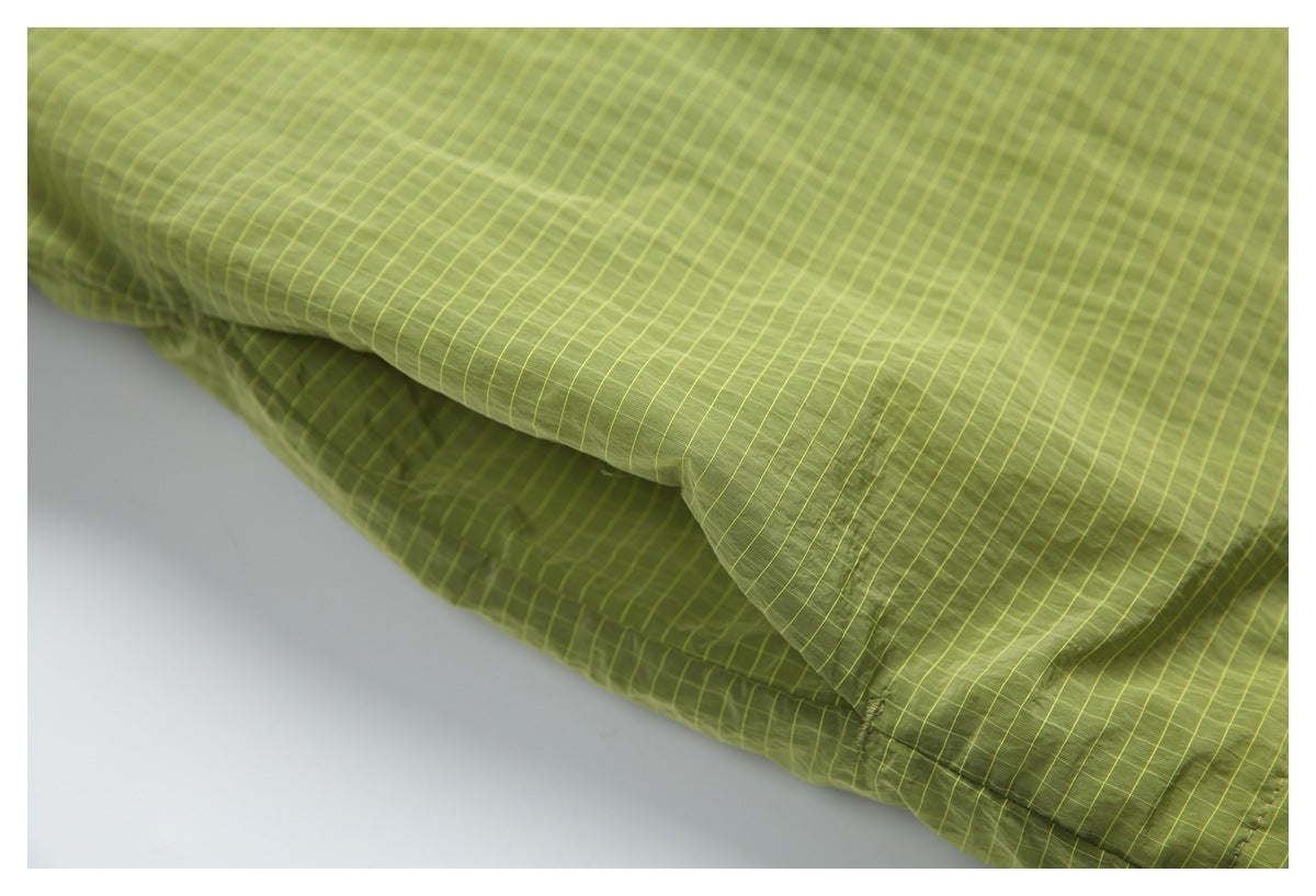 Close-up of olive-green grid-patterned fabric draped to show its texture and stitching.
