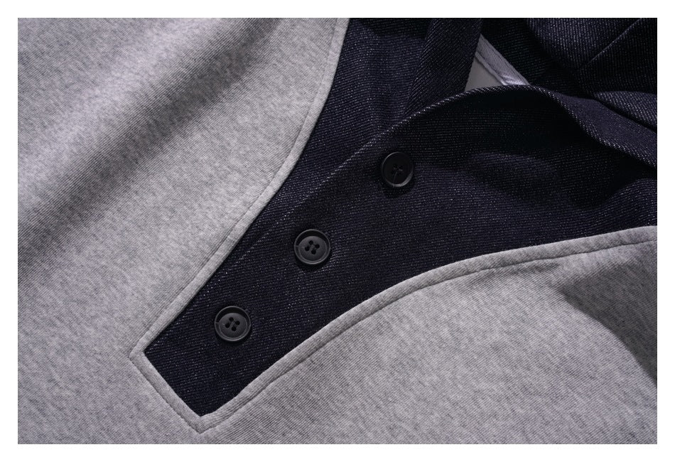 Close-up of a charcoal three-button placket framed by gray fabric on the hoodie front.