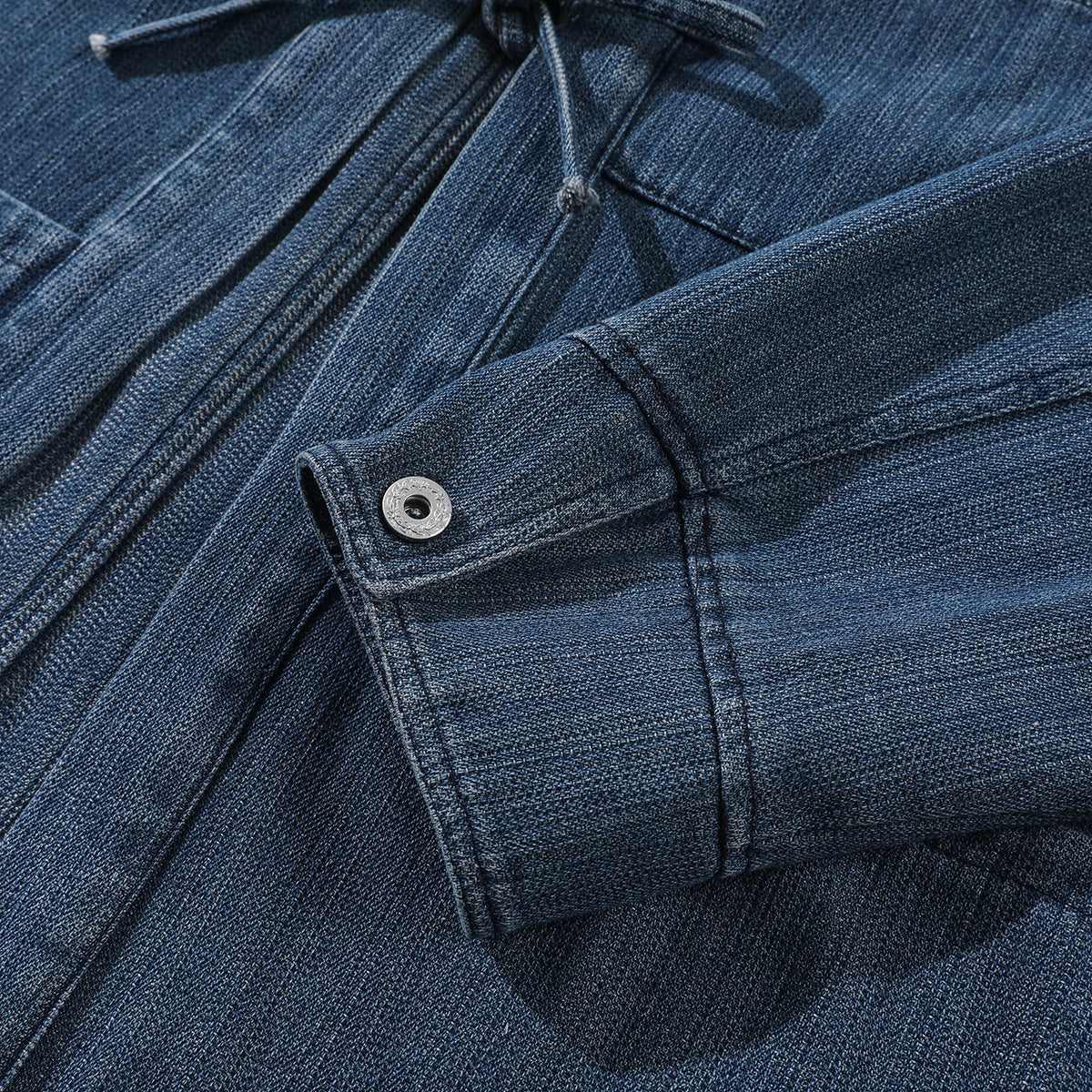 Close-up of a dark blue denim jacket sleeve cuff with a silver snap button.