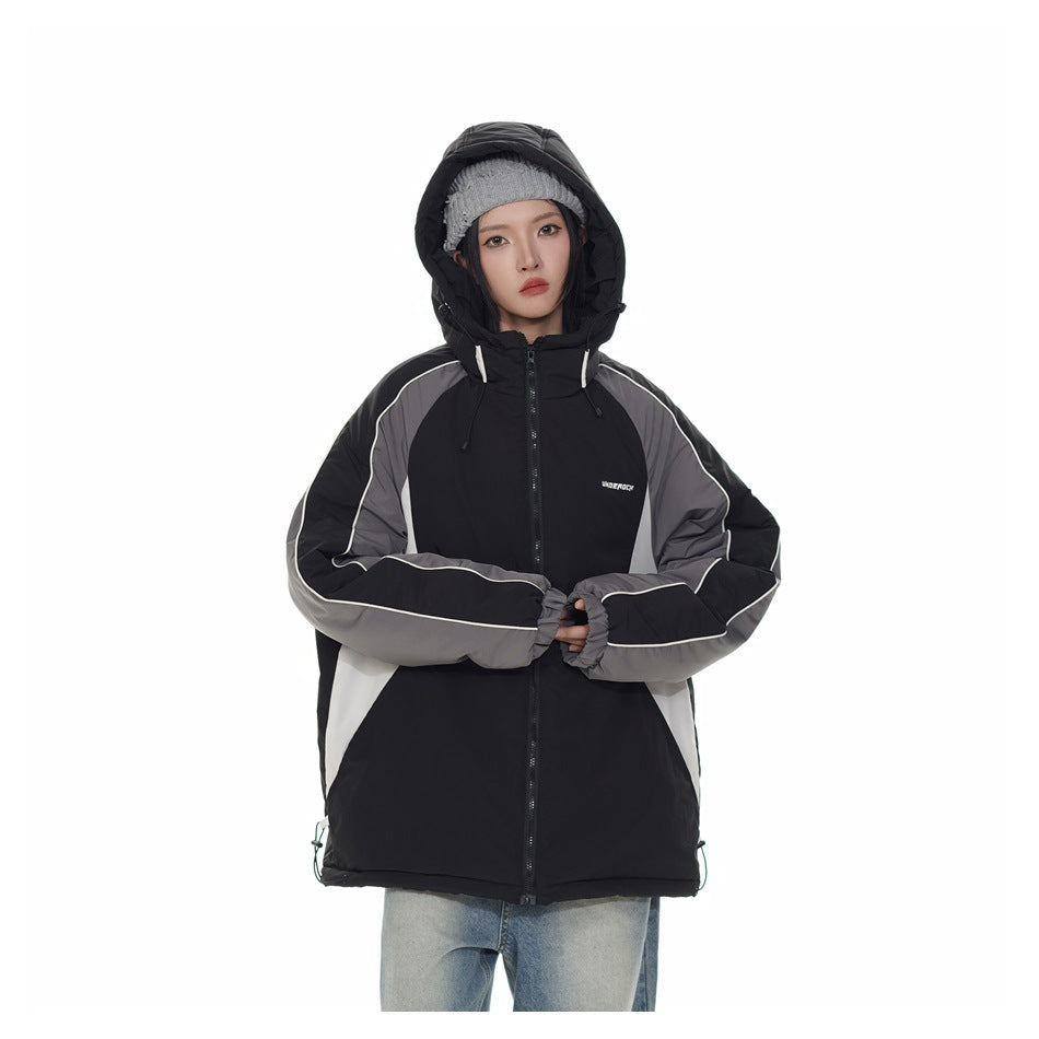 Model wearing a black hooded jacket with gray sleeves and white piping, hood up, with a gray beanie and jeans