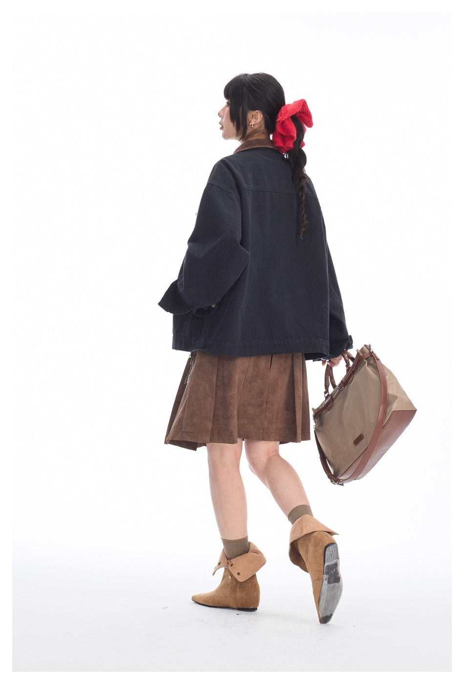 Model showing the back of a dark navy jacket with a brown collar, paired with a brown skirt and tan boots.