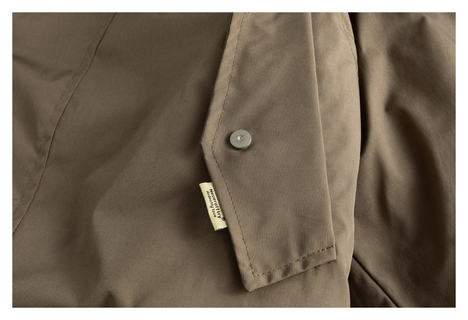 Close-up of a taupe-brown jacket flap with a round button and small sewn-in label.