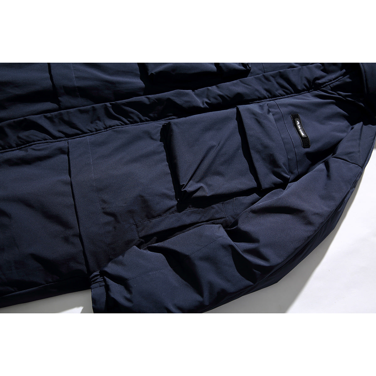 Close-up of a dark navy coat with large flap pockets and a small sewn label.