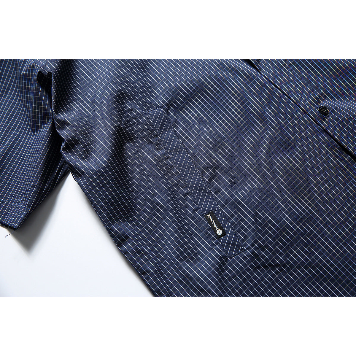 Close-up of the navy grid-check shirt's front pocket and button placket.