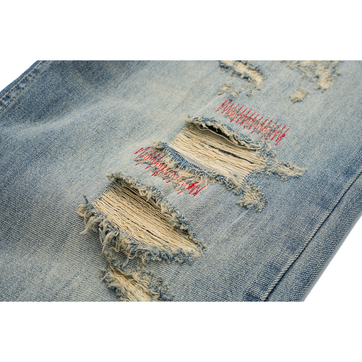 Close-up of distressed light-blue denim with frayed horizontal tears and red stitching.