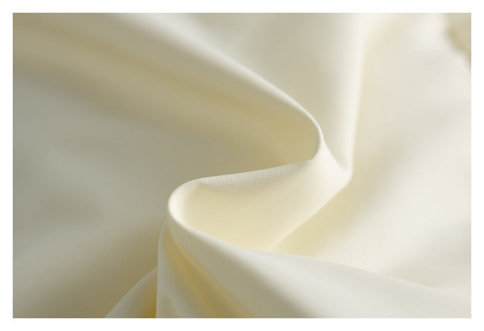 Close-up of smooth ivory fabric draped into a curved fold, revealing its fine texture.