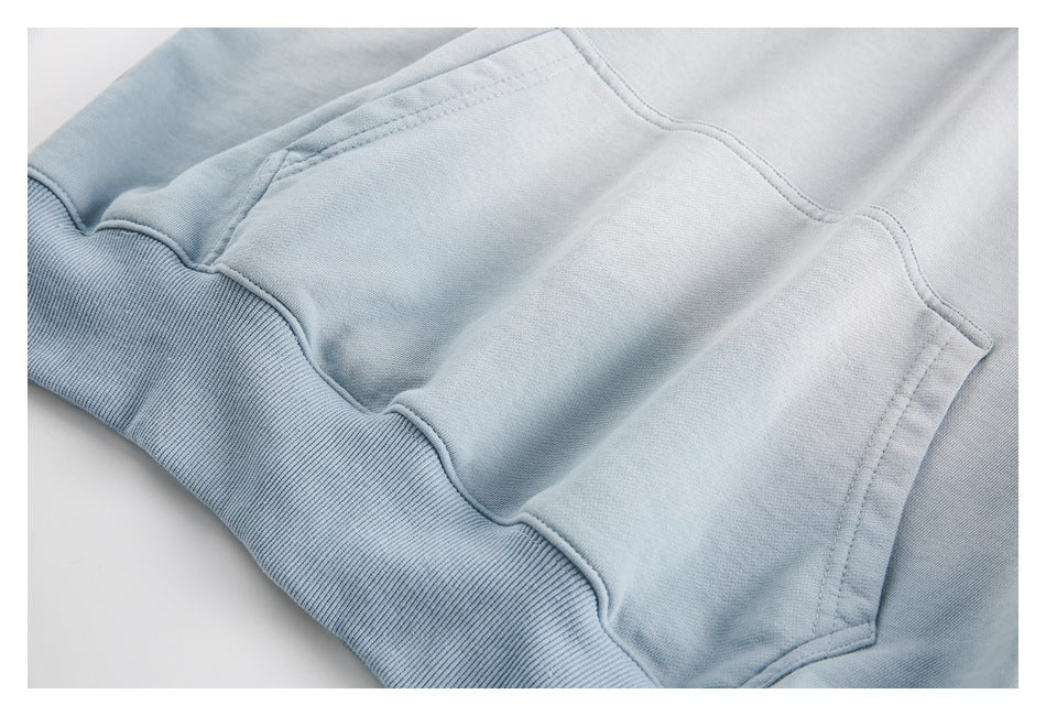 Close-up of a pale blue sweatshirt showing a ribbed band and curved stitched panel edges.