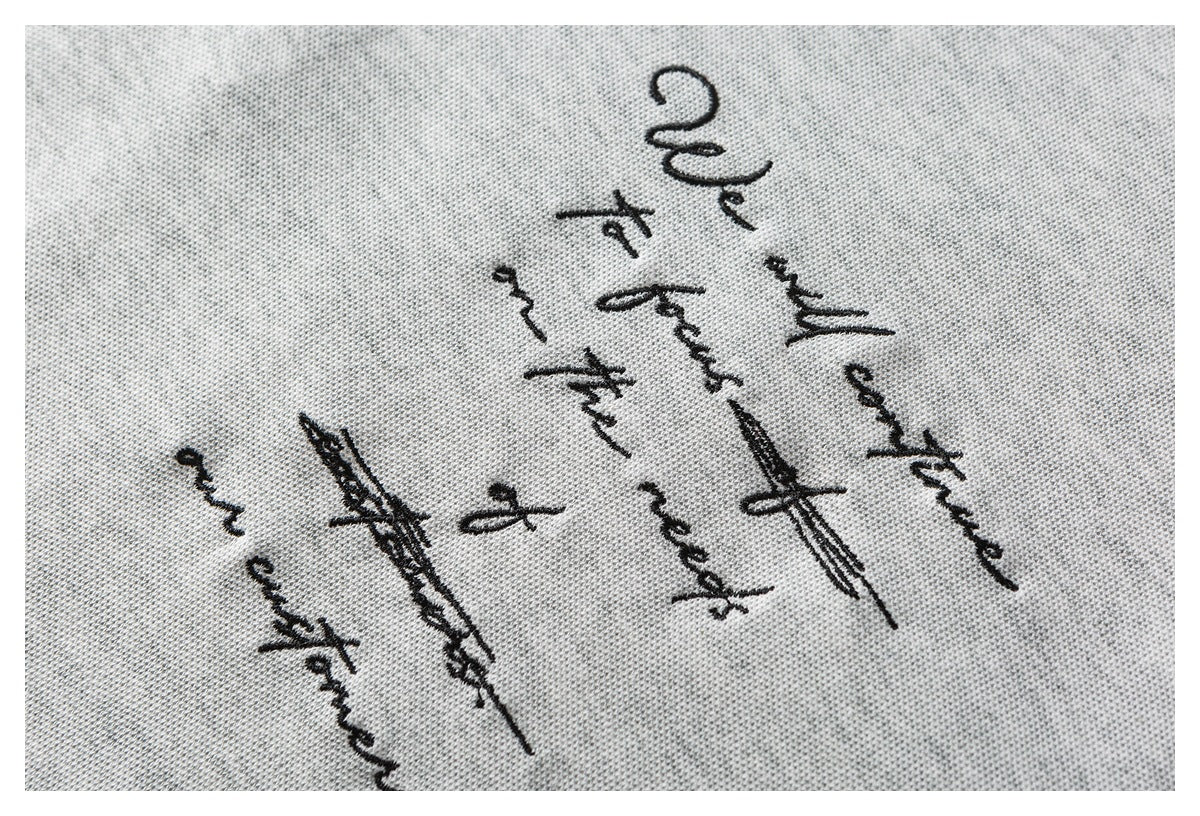 Close-up of black cursive lettering printed on light gray knit fabric.
