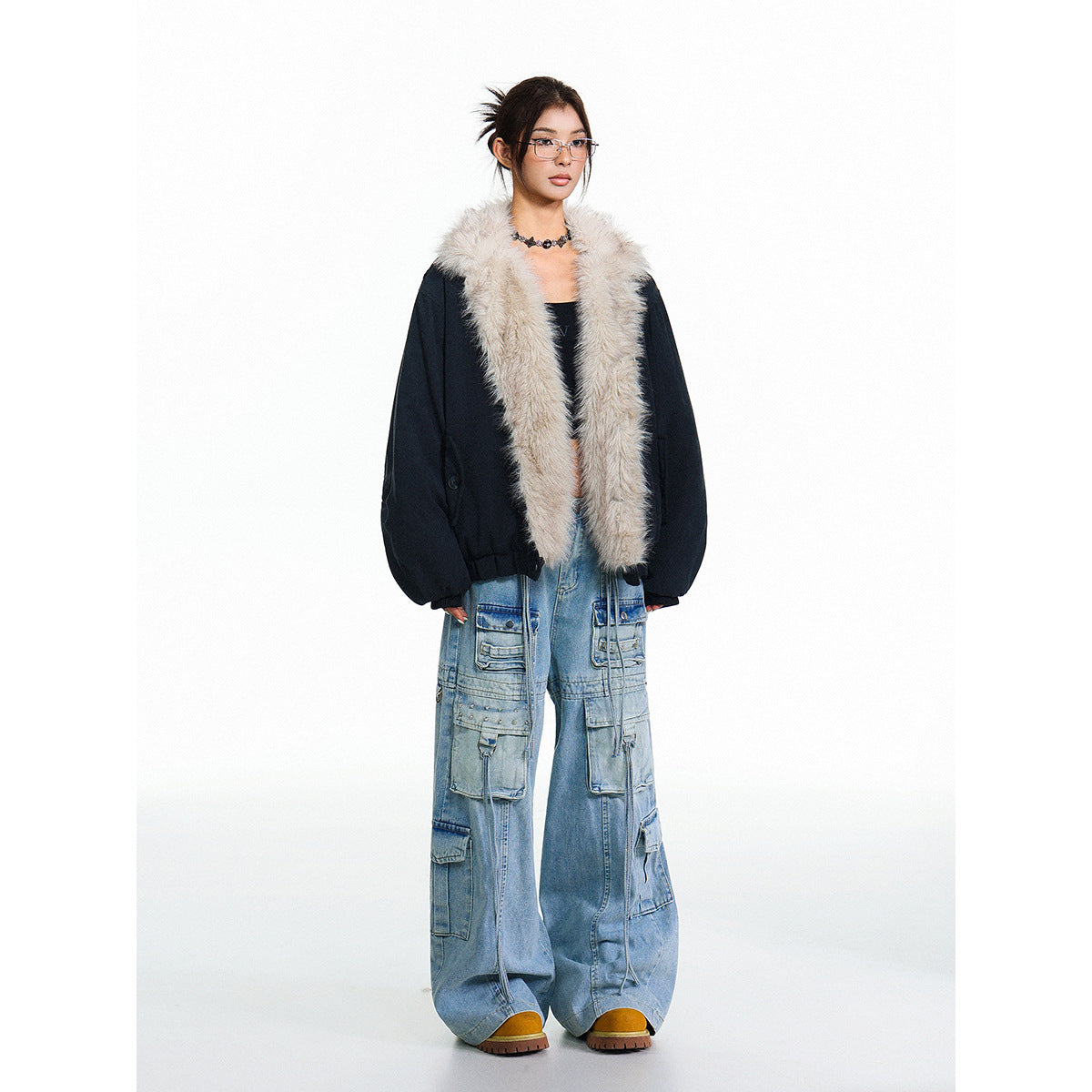 Full-length model wearing an open black jacket with long cream fur lapels and wide-leg cargo jeans.