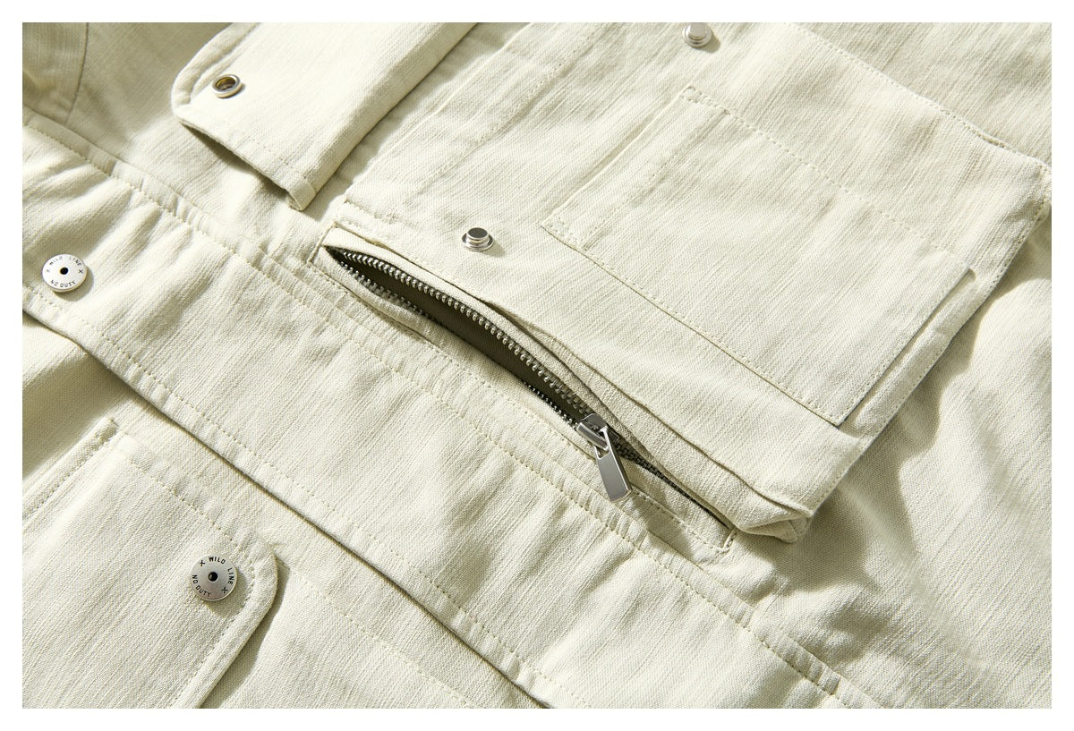 Close-up of an ivory jacket showing flap pockets, metal snaps, stitching and a diagonal silver zipper.