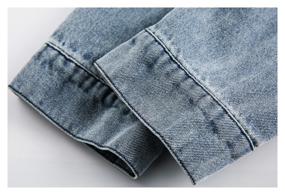 Close-up of a folded denim sleeve and stitched cuff in light blue denim.