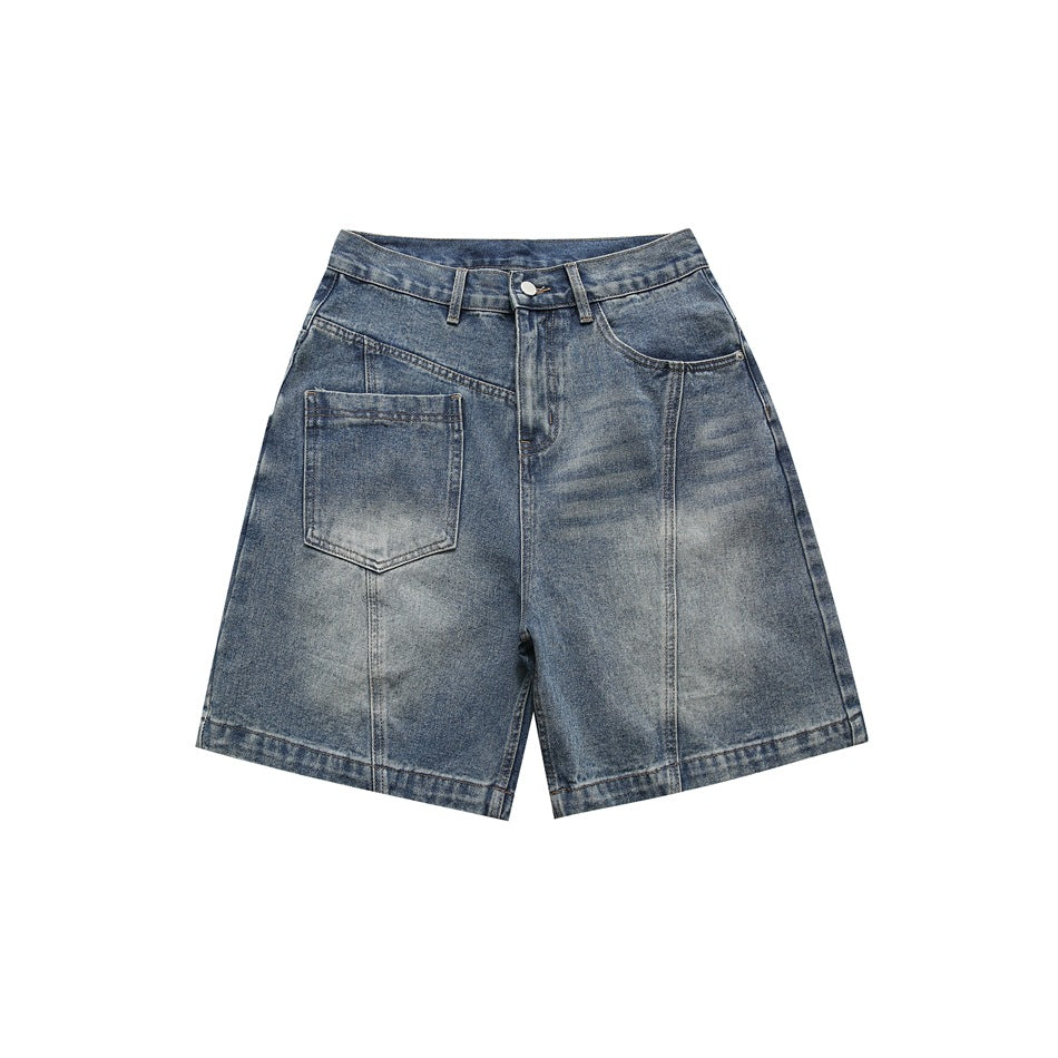 Front view of blue washed denim knee-length shorts with a large left patch pocket and diagonal seams