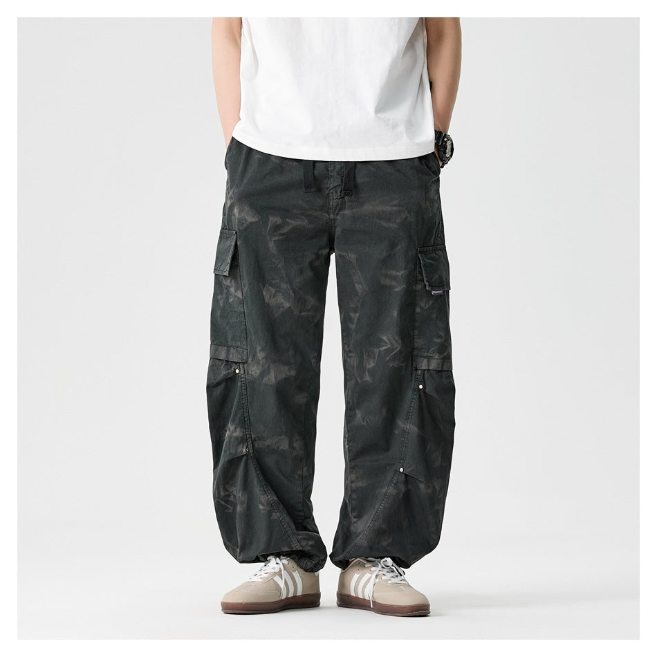 Straight-on front view of a model wearing loose charcoal cargo pants with multiple flap pockets.