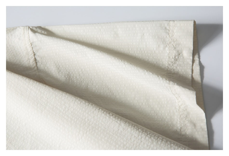 Close-up of an ivory shirt sleeve cuff and textured fabric, shown folded.
