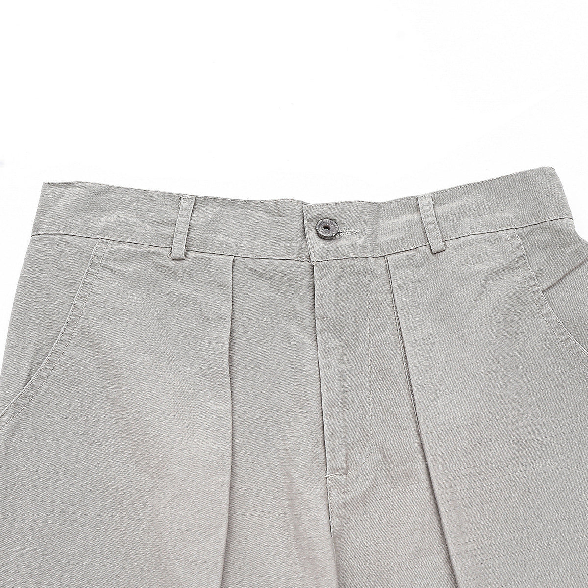 Close-up of light gray trousers showing the buttoned waistband, belt loops, front pleats, and curved pockets.
